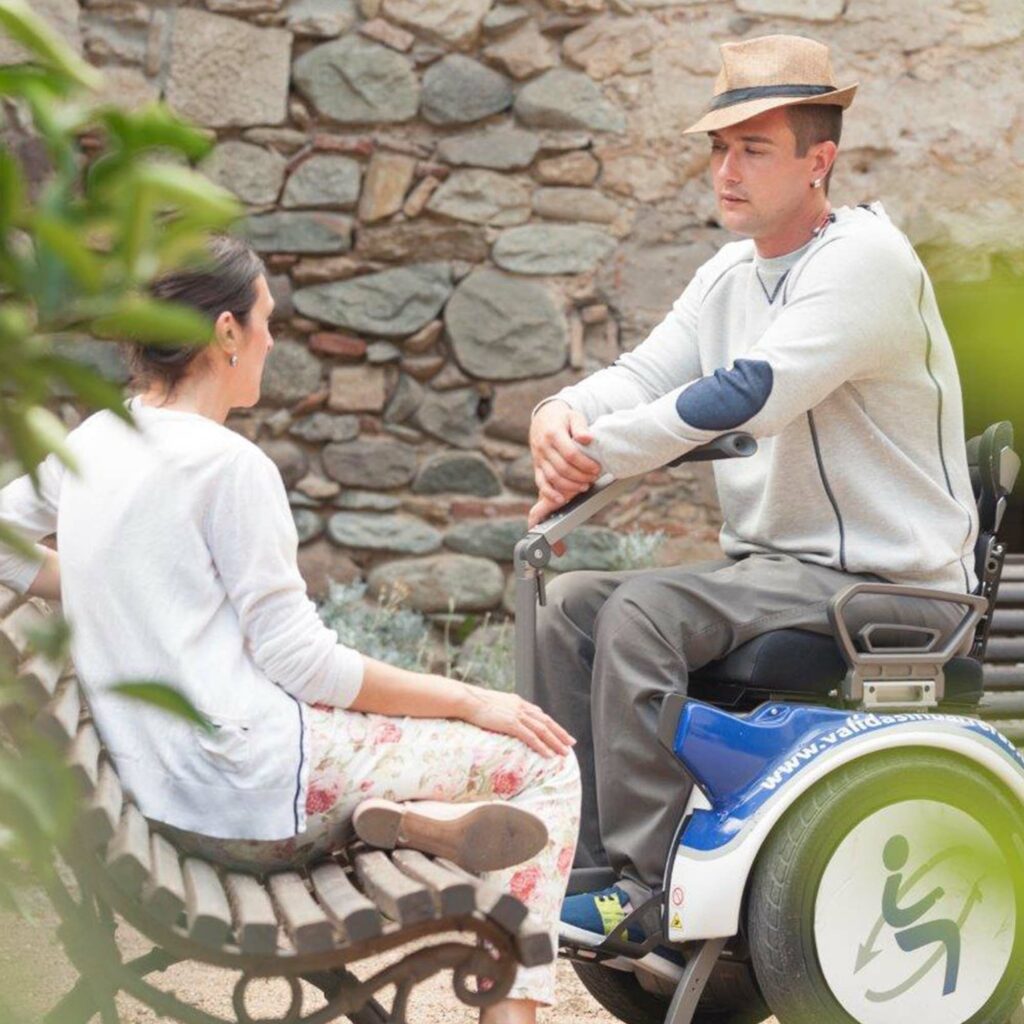 Imagen de Rut y Alex hablando. Alex va con su silla de ruedas.